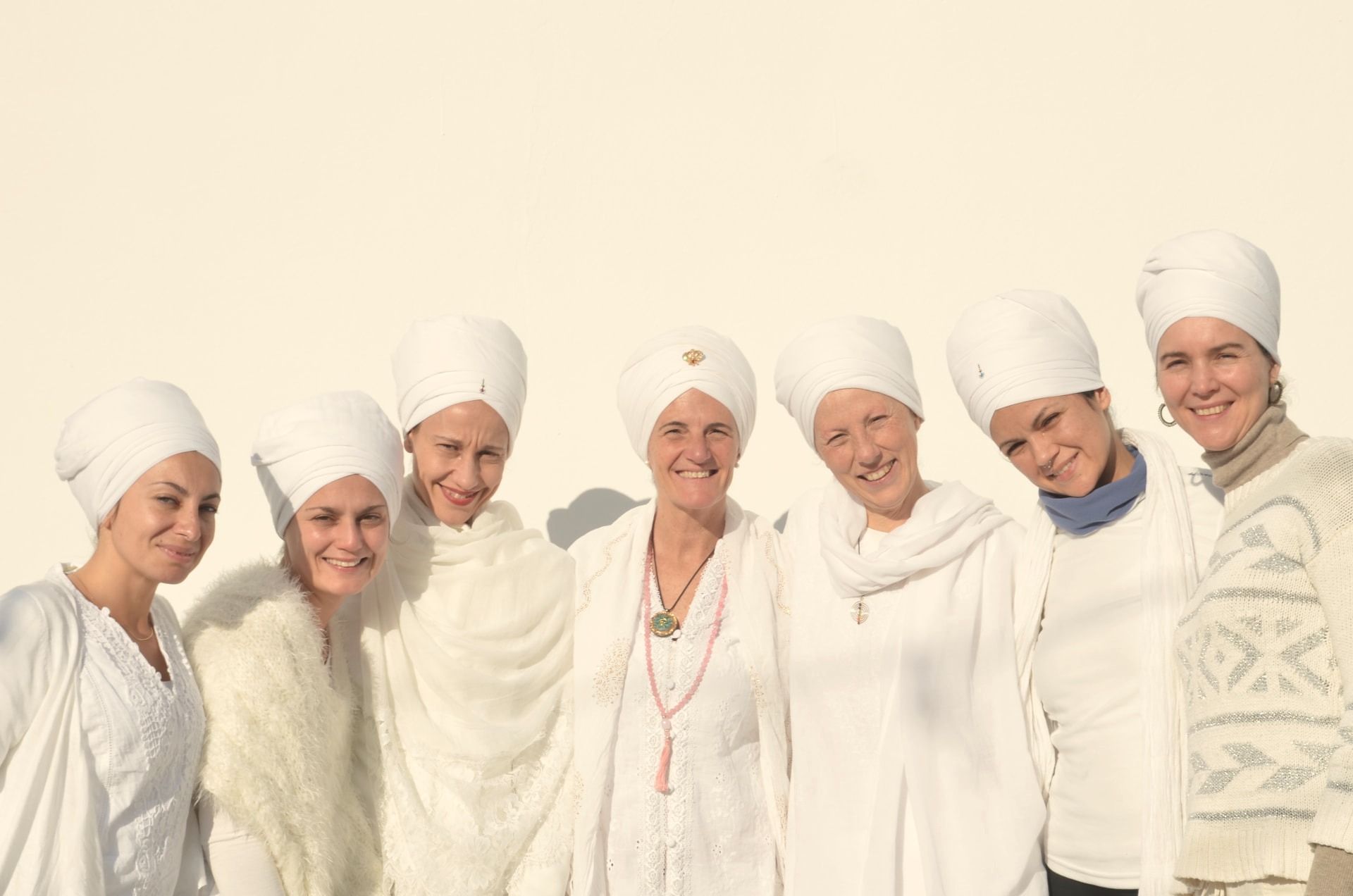 Grupo de mujeres con turbante blanco sonriendo tras una práctica de Kundalini Yoga